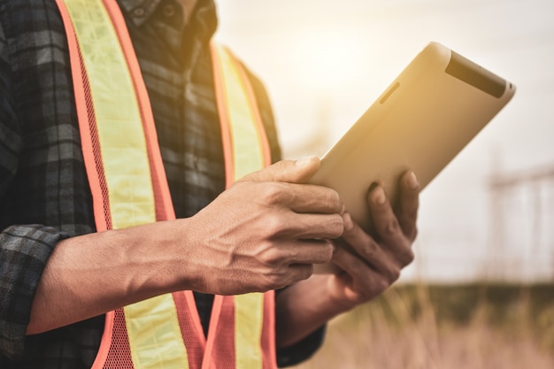 El ingeniero eléctrico usa una tableta para inspeccionar la red de la planta de energía Para la generación de energía