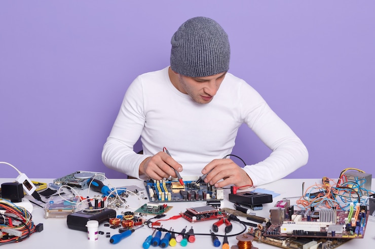 Foto ingeniero electrónico que mide el voltaje de la placa de circuito electrónico con la ayuda de multimete
