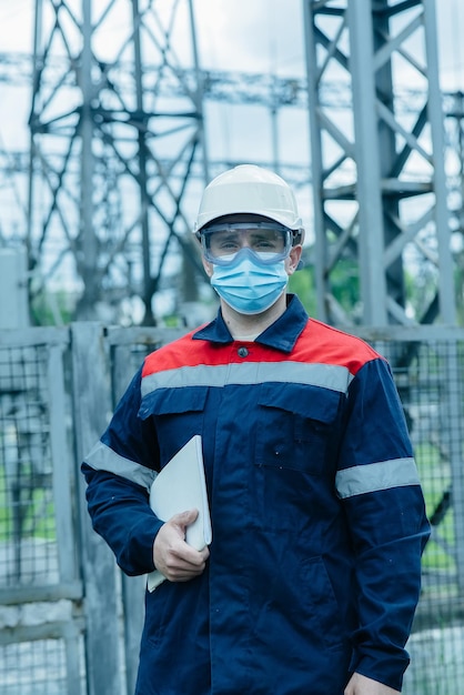 Un ingeniero energético enmascarado durante una pandemia inspecciona el equipo moderno de una subestación eléctrica antes de la puesta en marcha Energía e industria Reparación programada de equipos eléctricos