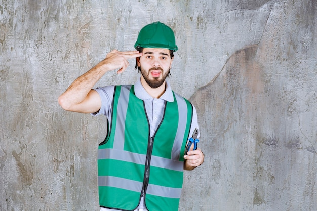 Ingeniero en engranaje amarillo y alicates de sujeción de casco.