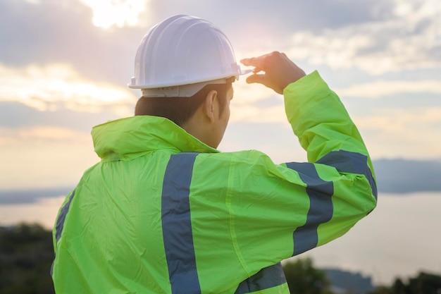 Un ingeniero le está poniendo un casco protector en la cabeza al atardecer.