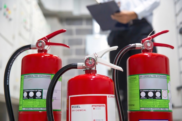 El ingeniero está revisando los extintores en la sala de control de incendios para prevenirlos.