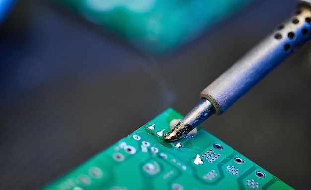 El ingeniero está soldando un chip de circuito de placa de computadora o un microchip Reparación de equipos de hardware Taller de reparación y trabajador con herramientas Prueba de dispositivos digitales modernos en el concepto de dispositivos electrónicos de escritorio