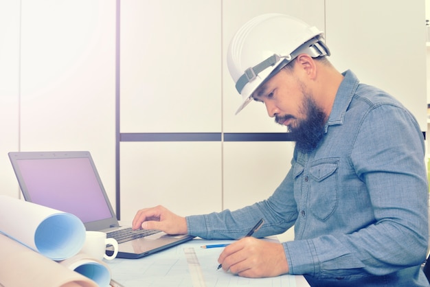 El ingeniero está trabajando en el escritorio con el plan de dibujo