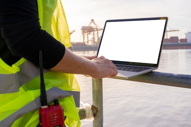 Un ingeniero está usando una tableta para trabajar. Está en el muelle de embarque. Use la comunicación por radio para notificaciones y órdenes de trabajo.