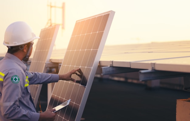 Ingeniero de la estación de paneles fotovoltaicos solares verificaciones con tableta. Concepto de tecnología energética