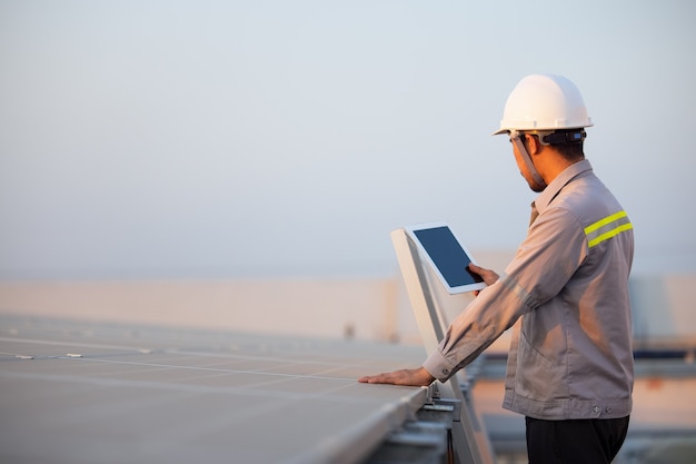 Ingeniero de la estación de paneles fotovoltaicos solares verificaciones con tableta. Concepto de tecnología energética