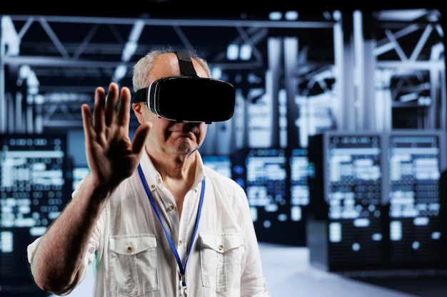 Ingeniero experto senior inmerso en la realidad virtual en el centro de datos, realizando mantenimiento de equipos. Experto en el uso de cascos de realidad virtual para optimizar el rendimiento del sistema del servidor, aprovechando tecnología de vanguardia