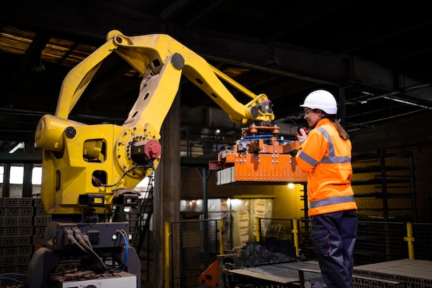 ingeniero de fábrica parado junto a una máquina robot industrial y observando el proceso de fabricación