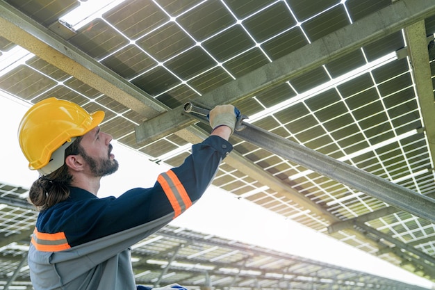 Ingeniero de fábrica revisando y reparando la construcción de paneles solares. El trabajador trabaja en una granja solar para energía renovable. Industria de células solares para la sostenibilidad.