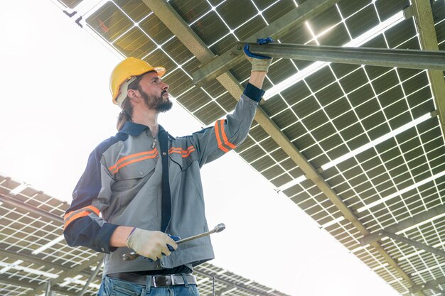 Ingeniero de fábrica revisando y reparando la construcción de paneles solares. El trabajador trabaja en una granja solar para energía renovable. Industria de células solares para la sostenibilidad.