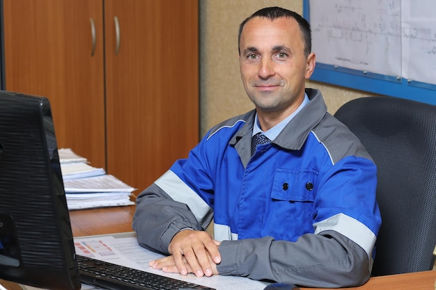 Ingeniero feliz sentado en su escritorio en una silla Retrato de un trabajador de producción