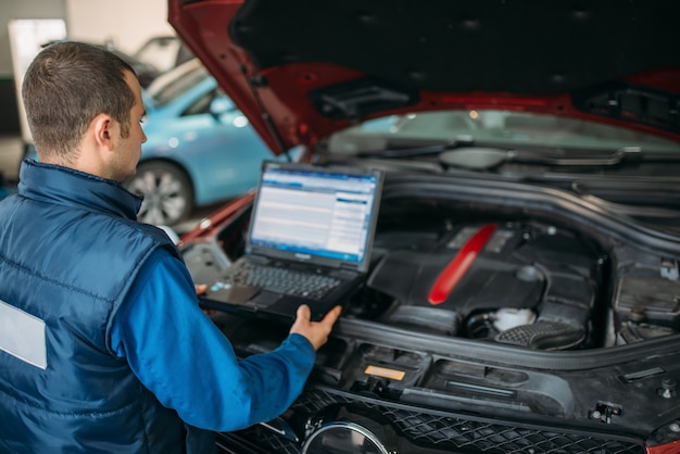 Foto el ingeniero hace diagnósticos informáticos del motor del automóvil