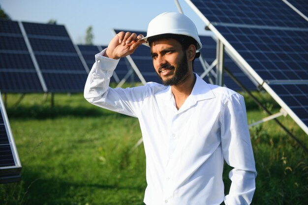 Un ingeniero indio con un chaleco verde está trabajando en un campo de paneles solares el concepto de energía renovable