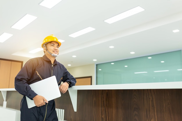 Ingeniero industrial en cascos de seguridad con casco, usa una computadora portátil con pantalla táctil.