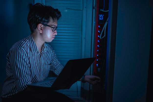 Ingeniero informático está configurando la red en la sala de servidores Técnico de Mantenimiento de Sistemas Ingeniero masculino trabajando en la habitación de servidores en un centro de datos moderno