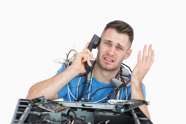 Ingeniero informático frustrado en llamada frente a la CPU abierta