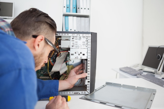 Foto ingeniero informático que trabaja en la consola rota con un destornillador