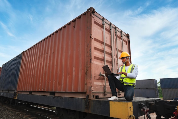 Ingeniero inspecciona un tren de contenedores de una empresa de transporte Distribución y transporte de mercancías por ferrocarril Un tren de contenidores que pasa por una zona industrial