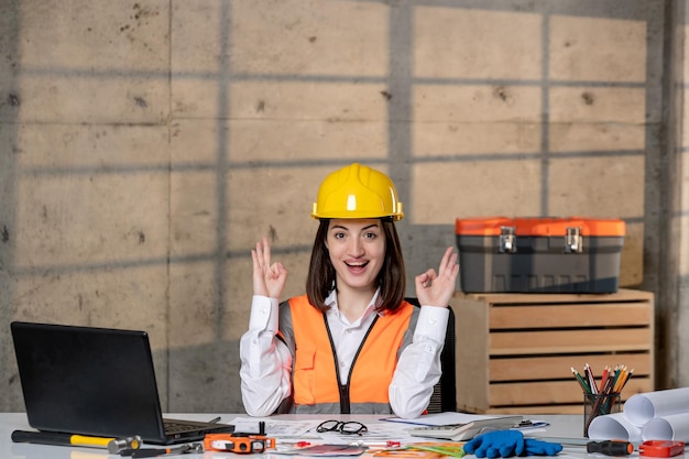 Foto ingeniero inteligente joven linda chica morena trabajador civil en casco y chaleco feliz