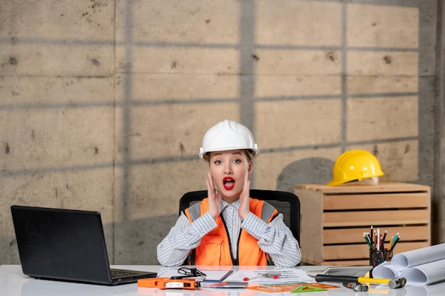 Ingeniero inteligente joven linda chica rubia trabajador civil en casco y chaleco gritando