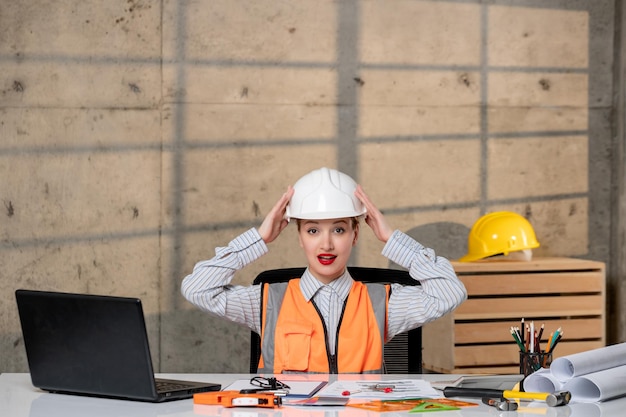 Foto ingeniero inteligente joven linda chica rubia trabajador civil en casco y chaleco quitándose el casco