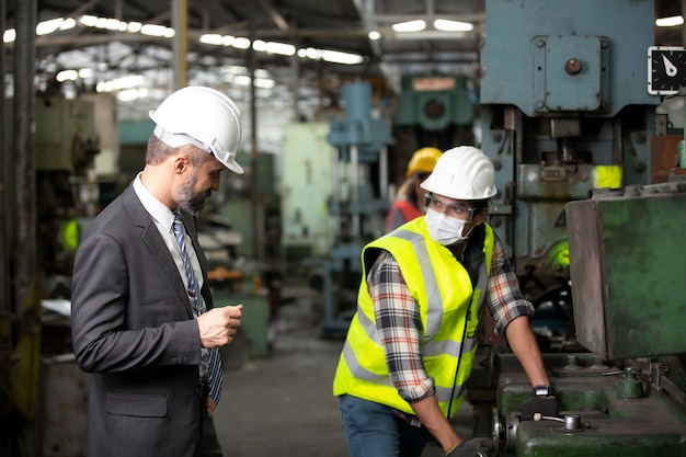 Ingeniero jefe y equipo de trabajadores de fábrica que controla la máquina en la línea de producción. Concepto de trabajo en equipo.