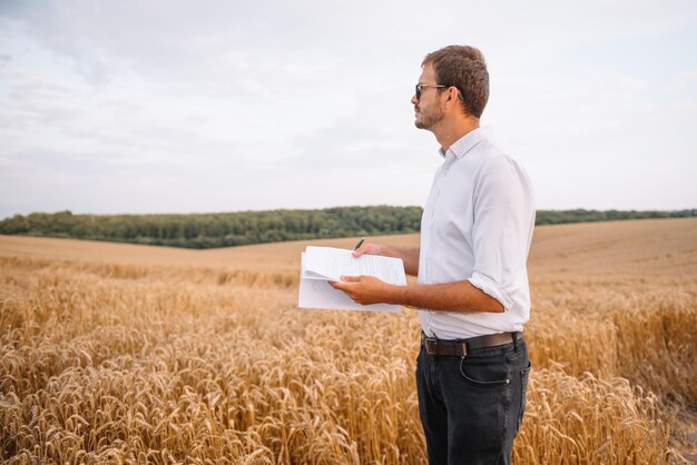 Ingeniero joven agricultor de pie en campo de trigo