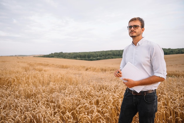 Ingeniero joven agricultor de pie en campo de trigo