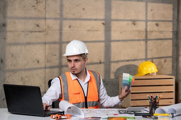 Ingeniero joven apuesto inteligente trabajador civil en casco y chaleco con paletas