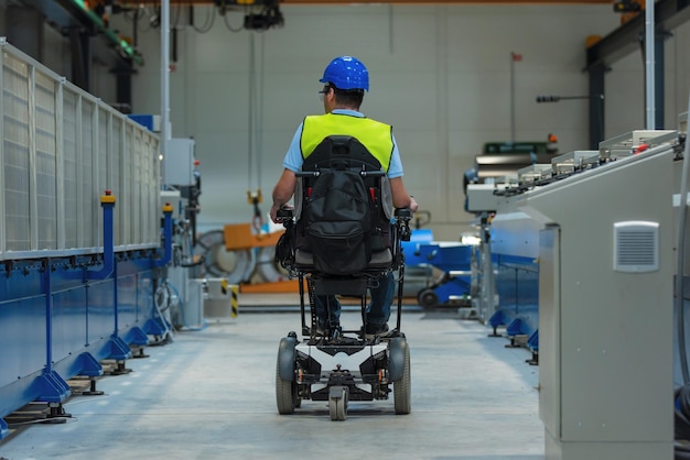 Ingeniero de línea de producción con discapacidad en una fábrica con chaleco amarillo y casco azul en el trabajo