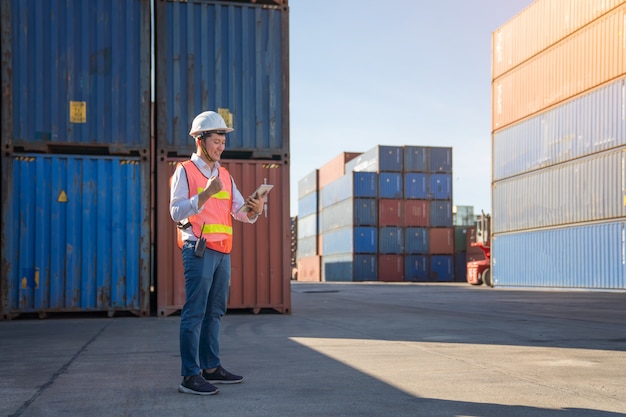 Ingeniero logístico de control en el puerto, cargando contenedores para camiones de exportación e importación logística