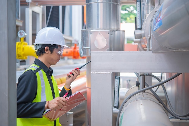 Ingeniero de mantenimiento asiático en el sistema de gestión de aguas residuales de una gran fábrica Mantenimiento comprobando los datos técnicos de los equipos del sistema de calefacción Gente tailandesa