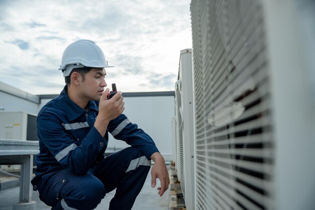 Foto el ingeniero de mantenimiento asiático trabaja en el techo del contratista de la fábrica inspecciona el sistema de compresores y planifica la instalación de sistemas de aire acondicionado en tecnología de construcción mantenimiento de walky talky