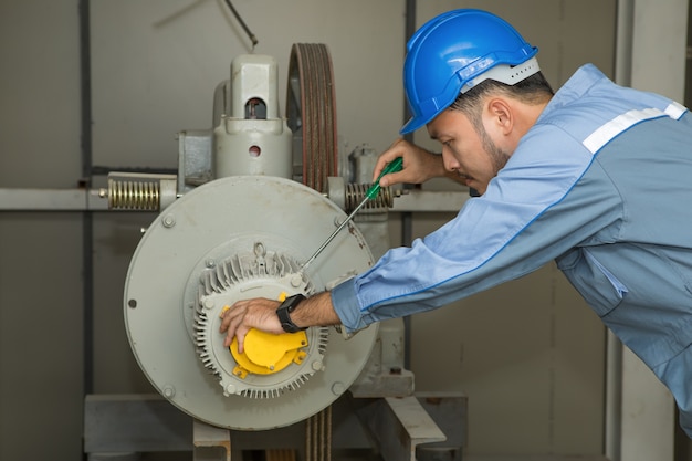 Foto ingeniero de mantenimiento que repara el motor de elevación para ascensores