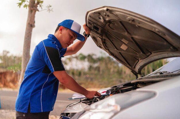 Ingeniero masculino asiático inspeccionando comprobando diagnosticando el motor del coche