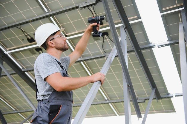 Ingeniero masculino en casco protector instalando sistema de panel solar fotovoltaico Concepto ecológico de energía alternativa