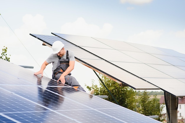 Ingeniero masculino en casco protector instalando sistema de panel solar fotovoltaico Concepto ecológico de energía alternativa