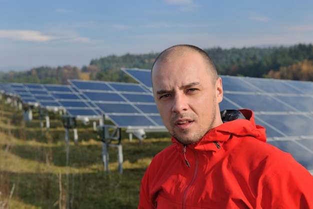 Ingeniero masculino en el lugar de trabajo, industria de plantas de paneles solares en segundo plano.