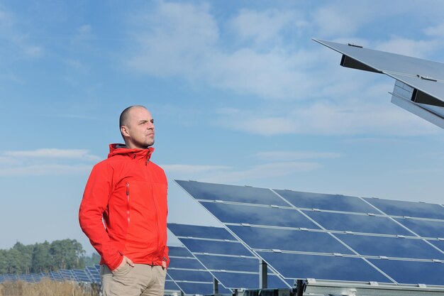 Ingeniero masculino en el lugar de trabajo, industria de plantas de paneles solares en segundo plano.