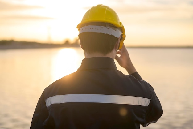 Un ingeniero masculino que lleva un casco protector al atardecer.