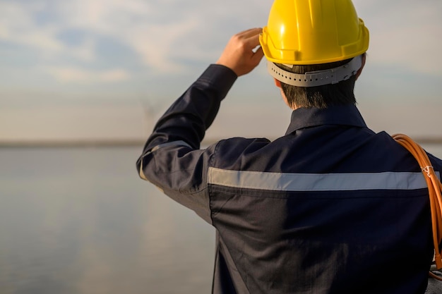 Un ingeniero masculino que lleva un casco protector al atardecer.