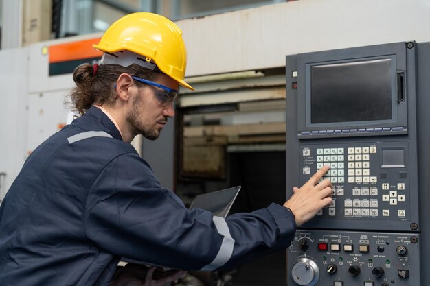 Foto ingeniero masculino que opera una máquina cnc en el panel de control de la fábrica