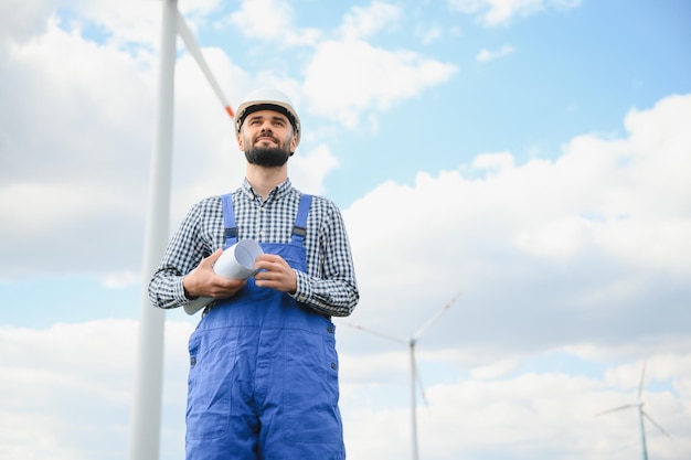 Ingeniero masculino que trabaja con planes de inspección o mantenimiento de turbinas eólicas en una granja de molinos de viento