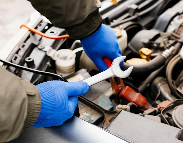 Ingeniero mecánico de automóviles utilizando una llave en proceso de reparación de un automóvil. Manos masculinas de mecánico con una llave trabajando en garaje. Hombre en guantes trabajando en la estación de servicio de reparación de automóviles.