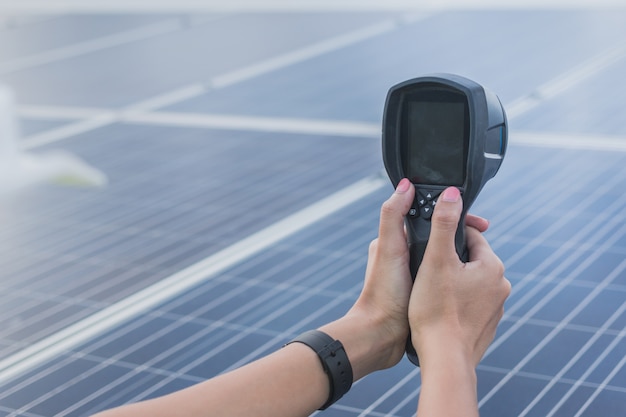 Ingeniero de la mujer usando una cámara termográfica para verificar la temperatura del calor del panel solar