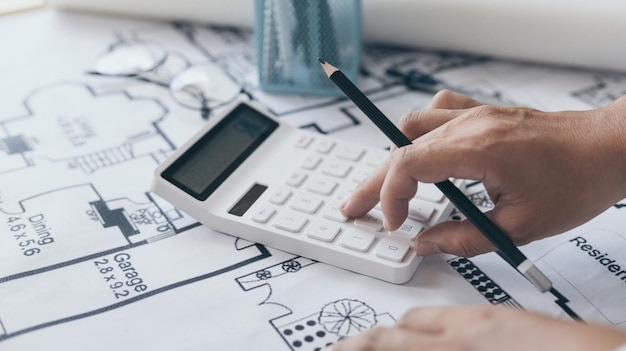 El ingeniero o el arquitecto está presionando una calculadora para calcular la estructura y el equilibrio de los edificios