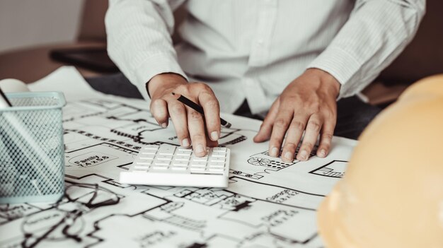 Foto el ingeniero o el arquitecto está presionando una calculadora para calcular la estructura y el equilibrio de los edificios