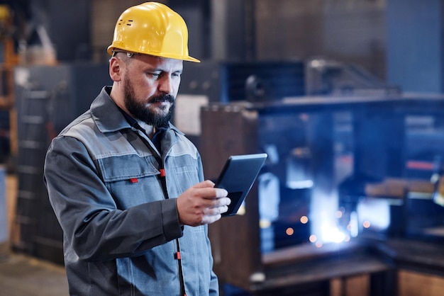 Ingeniero o constructor masculino en ropa de trabajo usando tableta para verificar datos sobre bienes