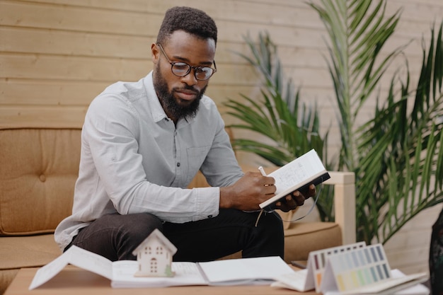 Un ingeniero o diseñador arquitecto afroamericano trabaja en una oficina en un edificio residencial